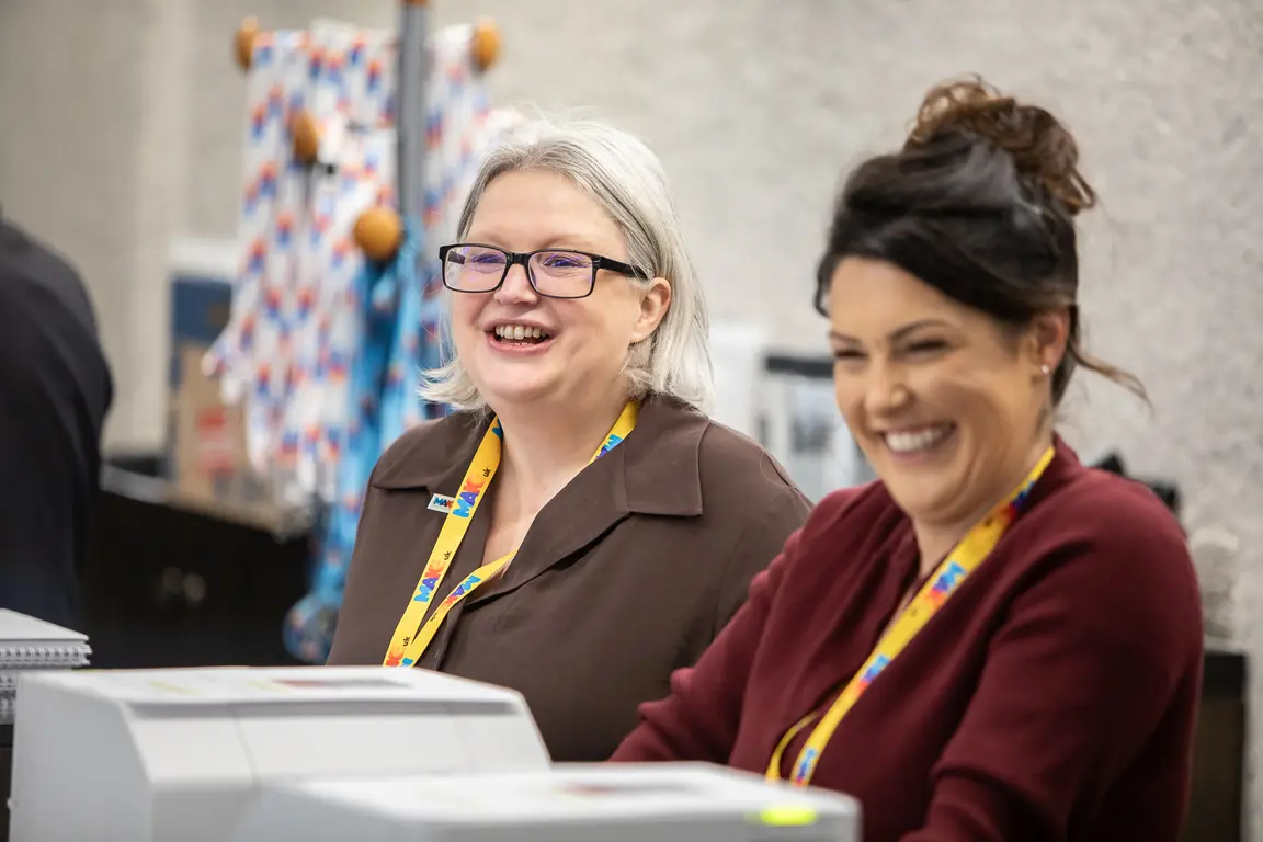 Two colleagues smiling as they greet guests
