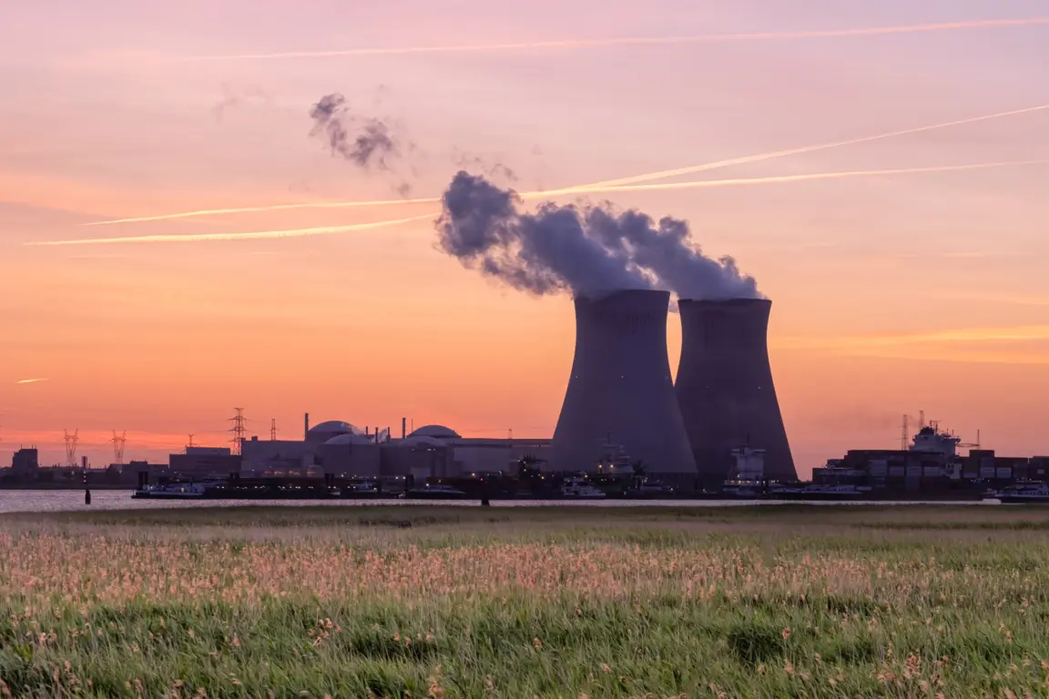 Two nuclear power plant towers with smoke rising from the top.