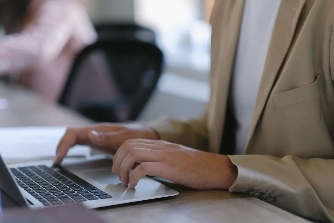 Office worker typing on a silver laptop.
