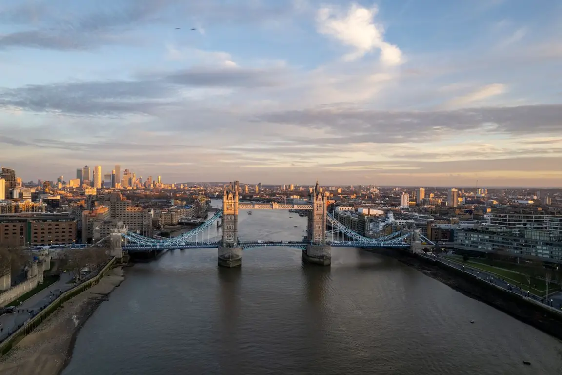 Aerial view of London skyline with Tower Bridge over the river at sunset.