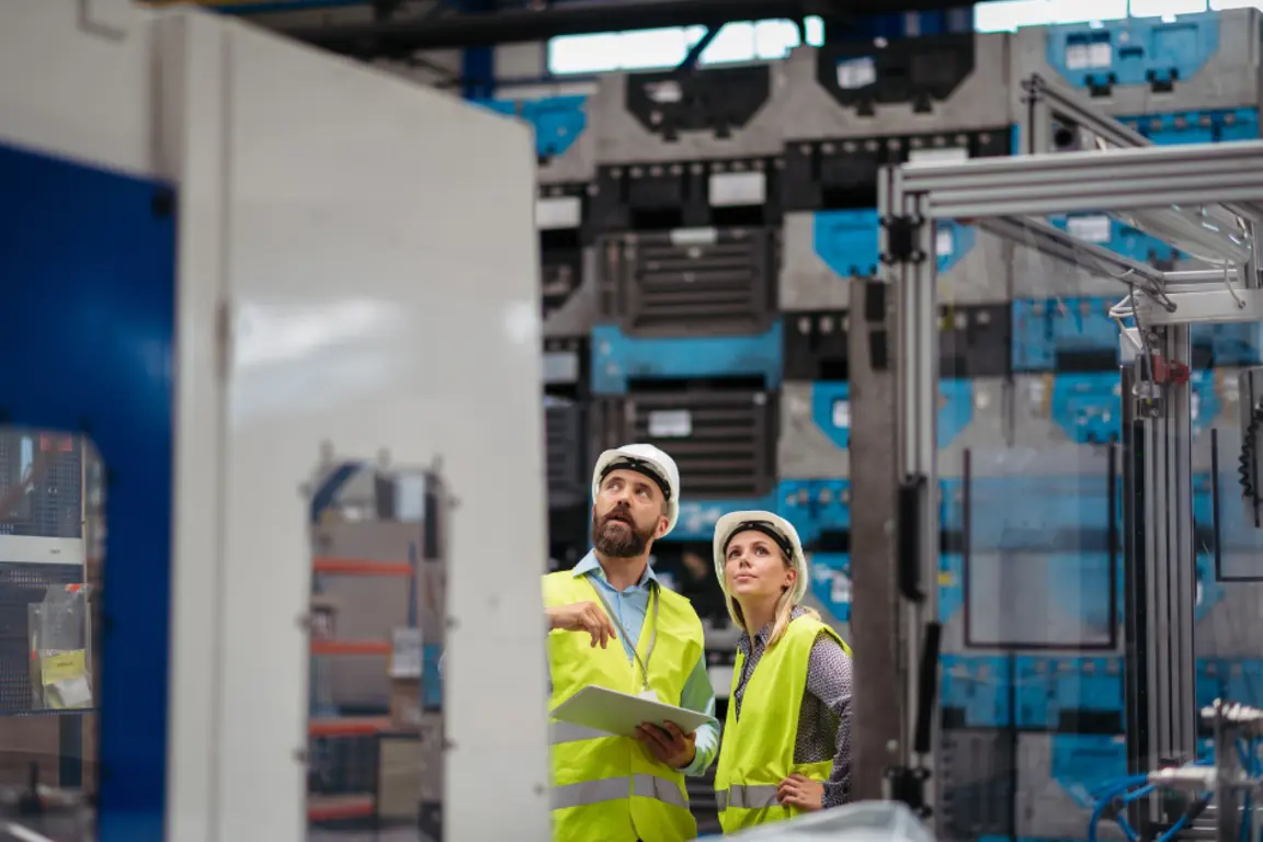 Two manufacturers, one male, one female examine factory machinery