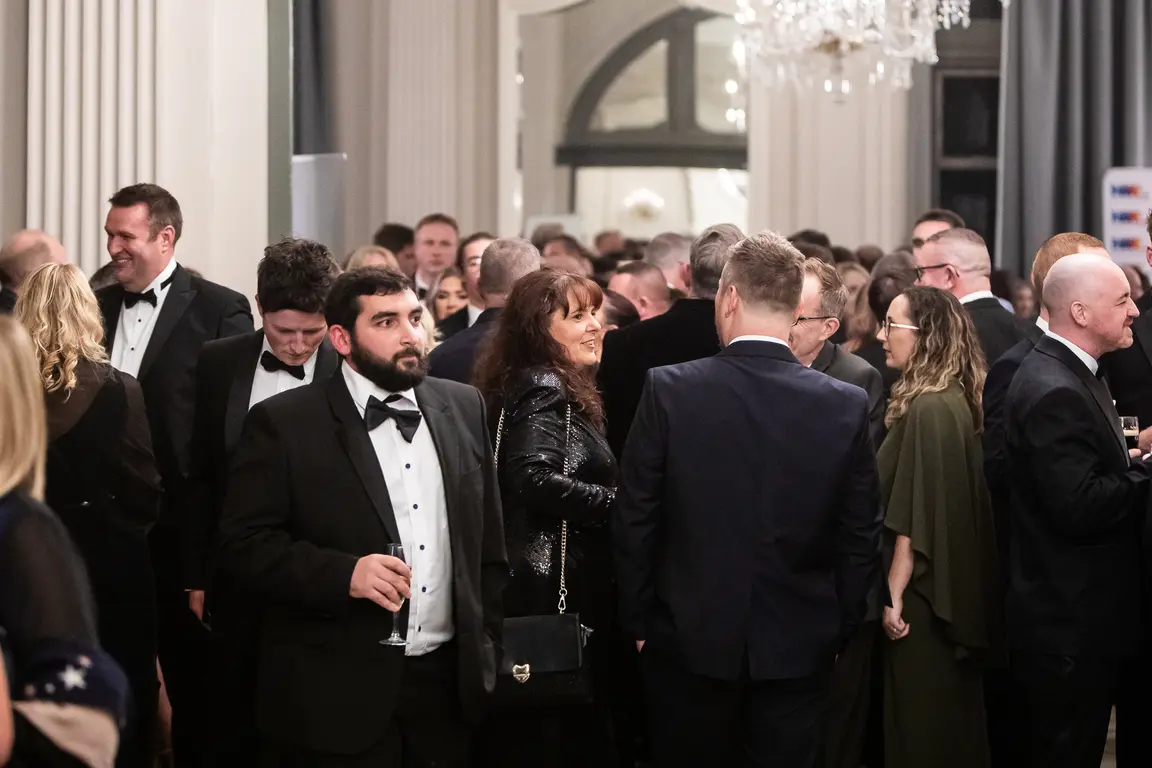 A large group of people in formal attire standing and talking at an event.