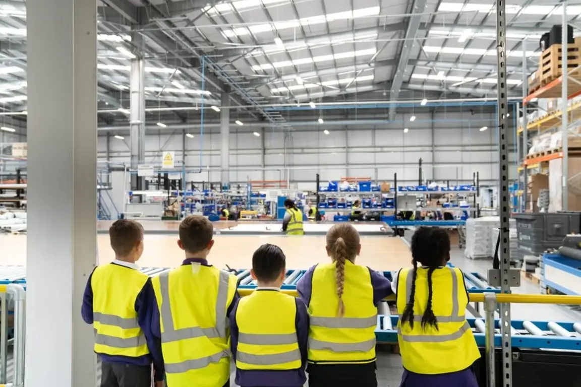 Schoolchildren with backs to camera look out into factory
