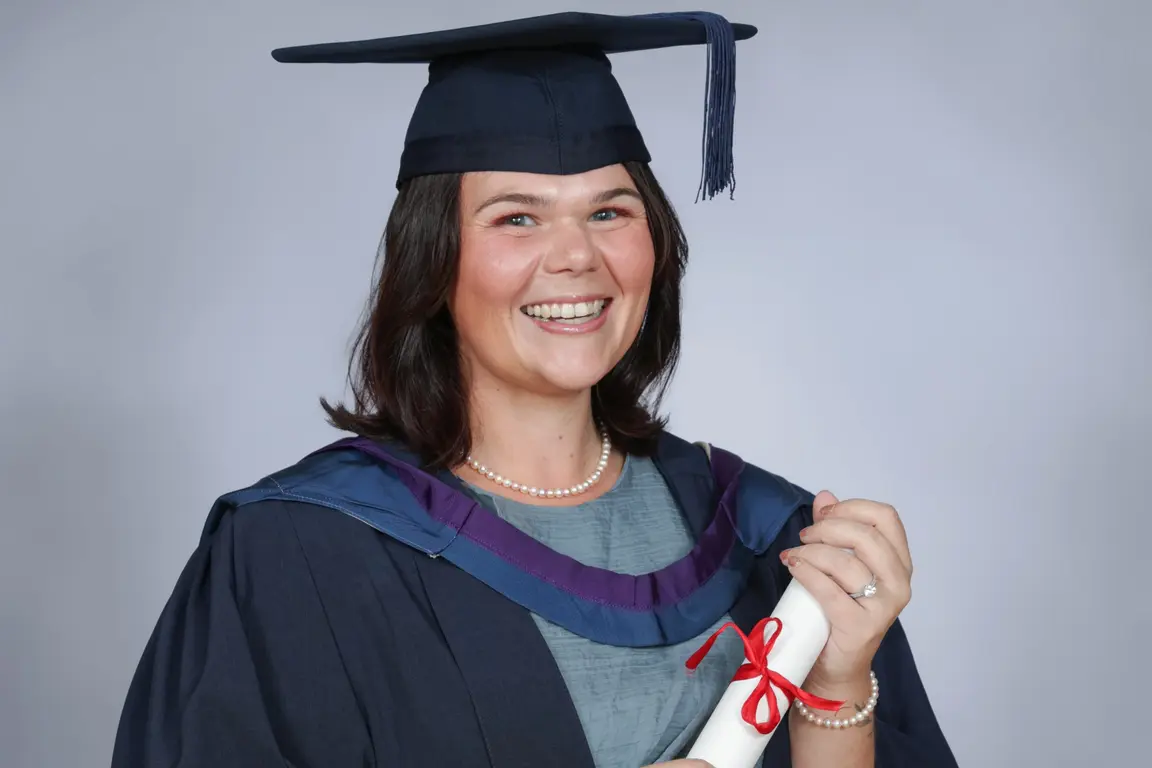 Woman in graduation gown holding a diploma