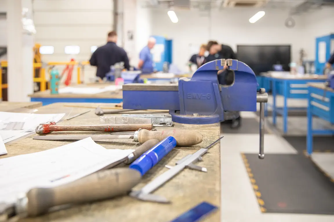 Workshop with tools and a blue vise on a table.