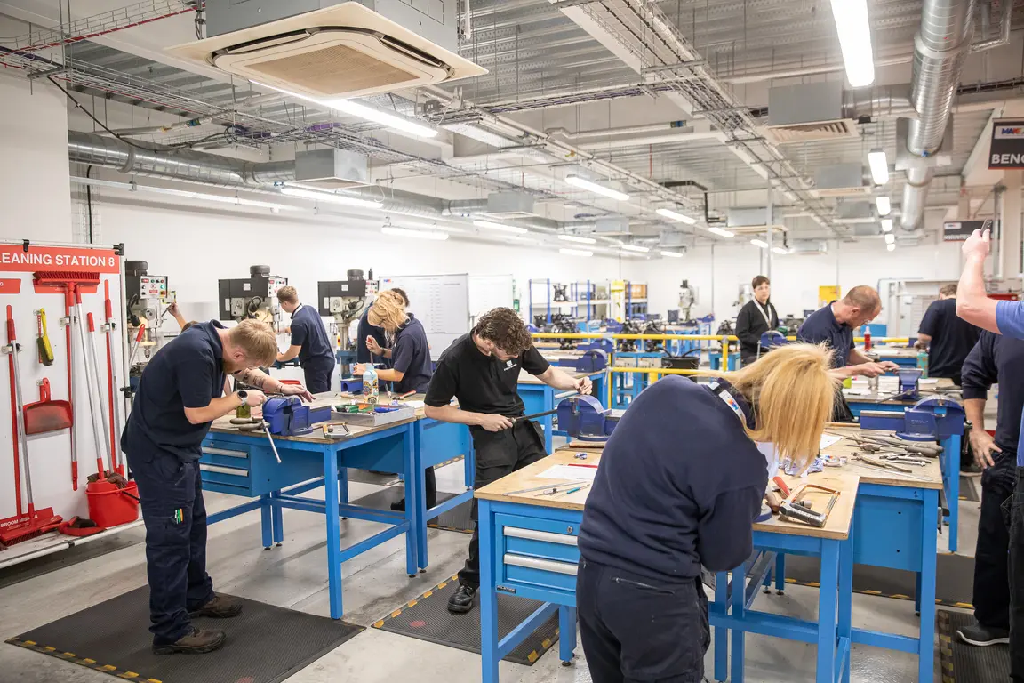 Several apprentices work in a shop with blue tables.