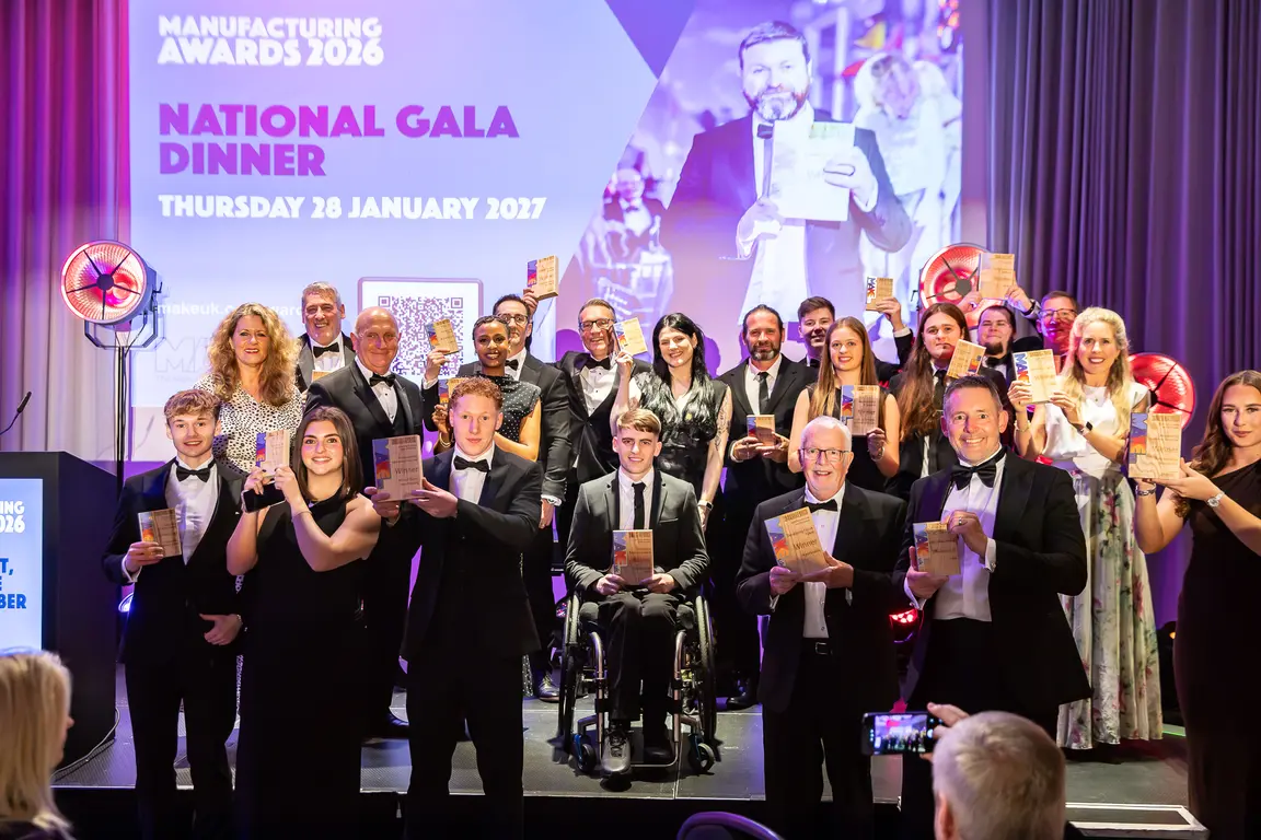 A group of people in suits pose with awards at a gala.