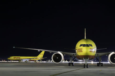 Two Trade cargo planes parked on a runway at night.