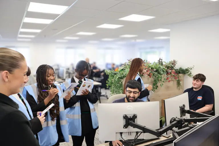 Six people in an office, looking at a computer monitor.