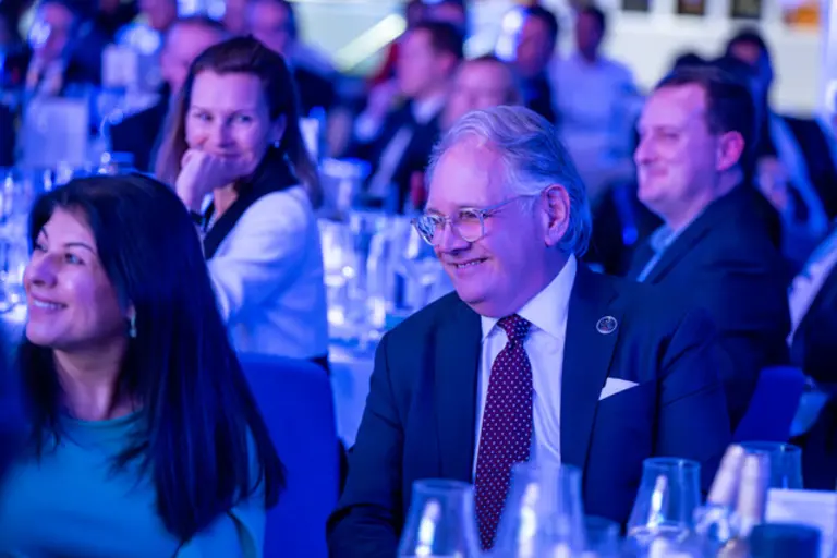 A man and woman in suits smiling at an awards ceremony