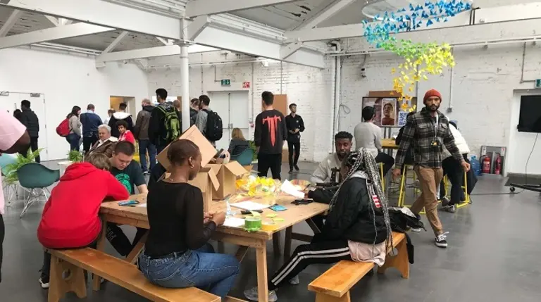 Shot of room with a table of young people in the foreground partaking in interactive activities
